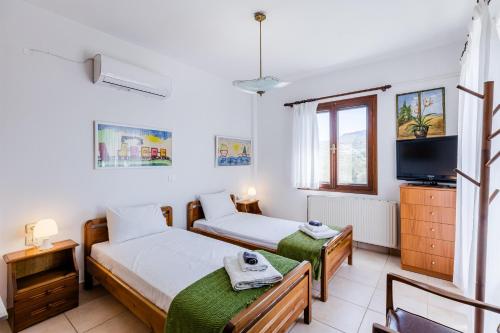 a bedroom with two beds and a tv at Demie's Maisonette in Plytra with SeaView in Plytra