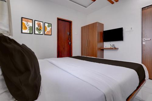 a bedroom with a white bed and a television at Hotel O Shree Lodging in Aurangabad