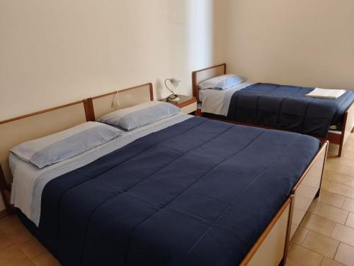 two beds in a hotel room with blue covers at Affittacamere Letizia Traballoni in Esanatoglia