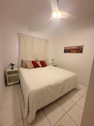 a bedroom with a white bed with a ceiling fan at Ap 2 Quartos em Caiobá, garagem, Wi-Fi in Matinhos