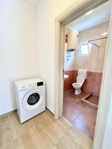 a bathroom with a washing machine and a toilet at B&V apartmani in Šušanj