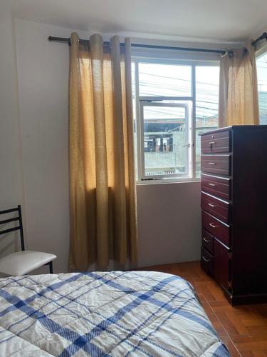 a bedroom with a bed and a dresser and a window at El refugio de Lolita, tu hogar en Loja in Loja