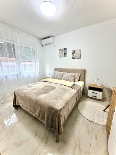 a bedroom with a large bed in a white room at Lucky apartman in Šabac