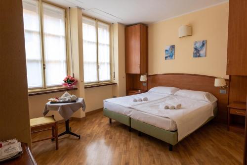 a bedroom with a bed and a table and windows at Hotel Saini with Air conditioning in Stresa