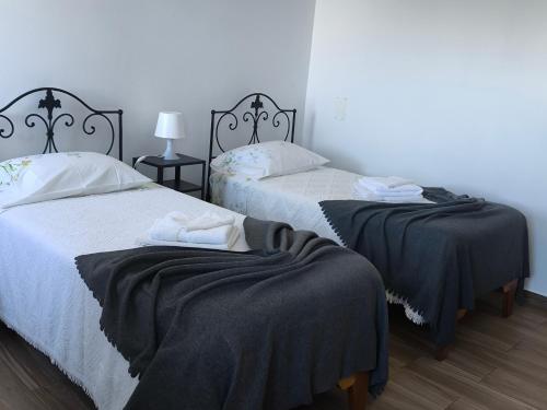 two beds with black blankets on them in a room at Casa do Marcelino Lagarto in São Roque do Pico
