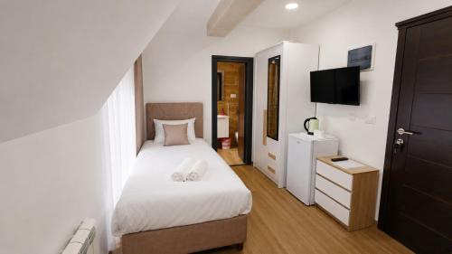a bedroom with a white bed and a television at Srebrna Jela in Žabljak