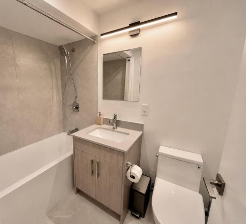 a bathroom with a sink and a toilet and a mirror at English Bay Hotel in Vancouver