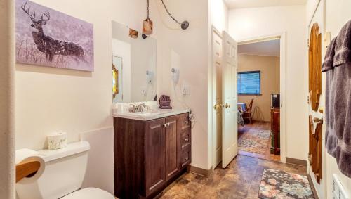 a bathroom with a toilet and a sink with a deer painting on the wall at Dodge Peak Lodge in Bonners Ferry