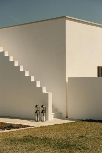 a white building with two stools next to a staircase at Tenute Allegretti Casa in Montalbano