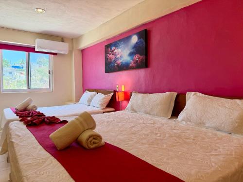 a bedroom with two beds and a pink wall at Hotel Barranquilla in Campeche