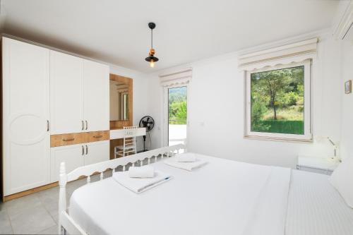 a white kitchen with white cabinets and a window at Villa Kısmet in Fethiye