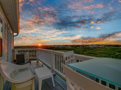 a balcony with a table and chairs and a sunset at Oceanfront with Private Beach Access Sunset Views in Sneads Ferry
