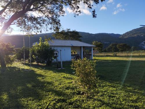 a small white house in a field with a tree at Sítio Azevedo in Buenópolis