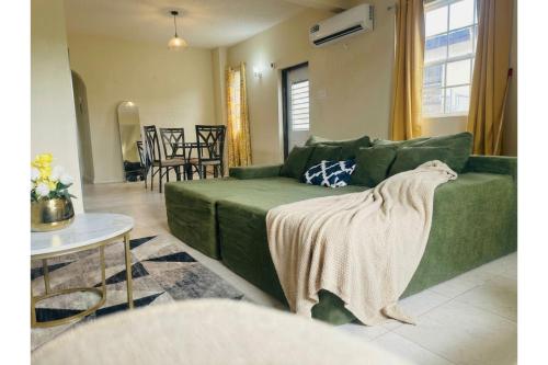 a living room with a green couch with a blanket at Casa Amarilla St Michael in Bridgetown