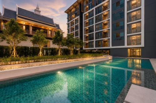 a swimming pool in front of two buildings at Cozy 1 BR Bangtao Beach in Laguna Phuket