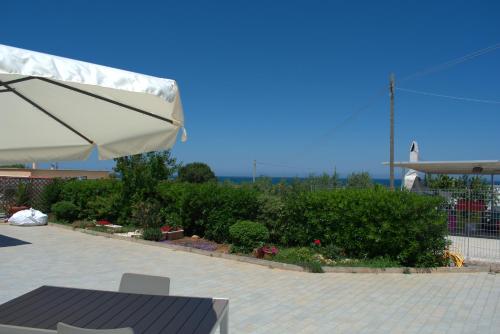 a patio with a table and an umbrella and bushes at Kasamare- Monopoli in Monopoli