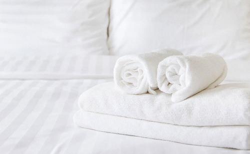 a pile of towels sitting on top of a bed at Charles Wesley Motor Lodge Downtown Broken Bow- Hochatown in Broken Bow