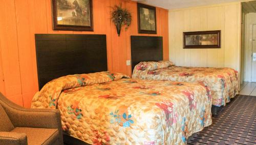 two beds in a hotel room with orange walls at Charles Wesley Motor Lodge Downtown Broken Bow- Hochatown in Broken Bow