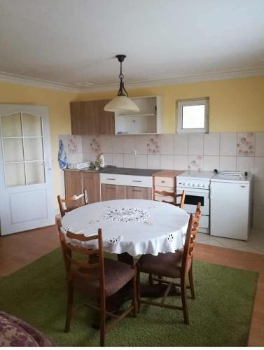 a kitchen with a table with chairs and a white tablecloth on it at Studio u selu Mačkat in Mačkat