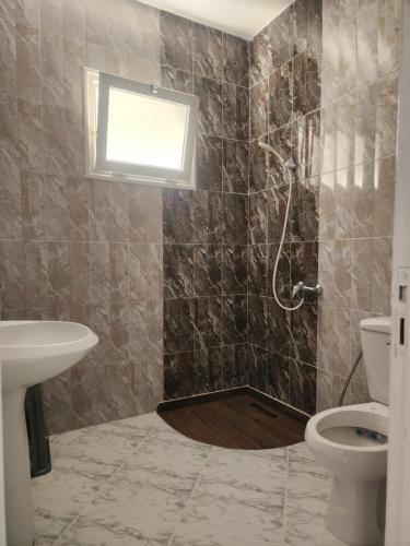 a bathroom with a shower with a sink and a toilet at F3 entre nature et calme in Raʼs al Jabal