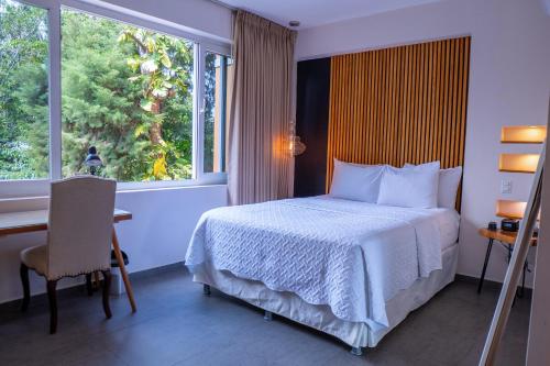 a bedroom with a bed and a desk and a window at Kaleo Hotel Boutique in San Salvador