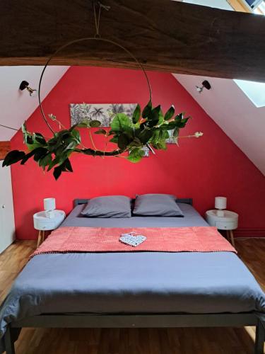 a bedroom with a bed with a red wall at Le Petit Moulin de Verberie in Verberie