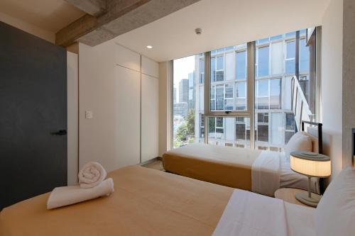 a bedroom with two beds and a large window at Nido x Nomad Pablo Neruda GDL in Guadalajara