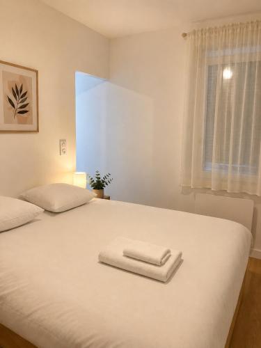 a white bed with two towels on top of it at LE 23 ter in Jarny