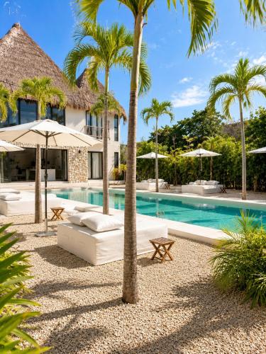 a resort pool with palm trees and umbrellas at Villa Luxauthentika Tulum in Tulum