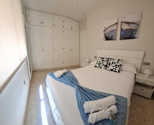 a bedroom with a large white bed with towels on it at Twin Beach in Torrenueva