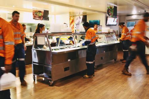 Un grupo de personas de pie en un mostrador de un restaurante. en Capricorn Village, en Newman