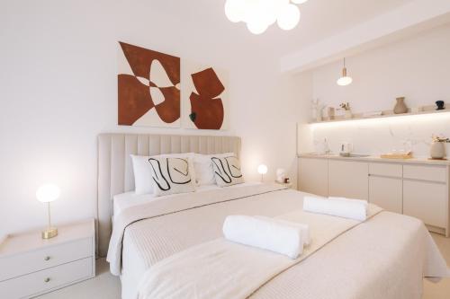a white bedroom with two beds and a kitchen at NUA Apartments in Ulcinj