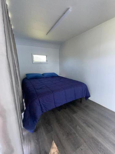 a bedroom with a bed with blue sheets and a window at Whistler - Apple Pod in Klamath