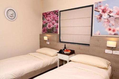 two beds in a room with a clock on the wall at Achuza Bamarom in Safed