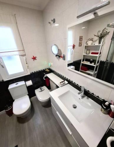 a bathroom with a white toilet and a sink at Dúplex 4 dormitorios Playa Foz in Foz