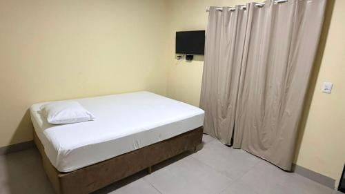 a small bedroom with a bed and a curtain at Hotel Rocha in Novo Acordo