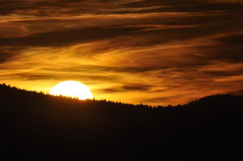 einen Sonnenuntergang über einem Hügel mit der Sonne am Himmel in der Unterkunft Pension Harmonia in Miercurea Ciuc
