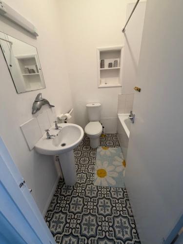 a white bathroom with a sink and a toilet at Captain Normans Sea view in Hollington