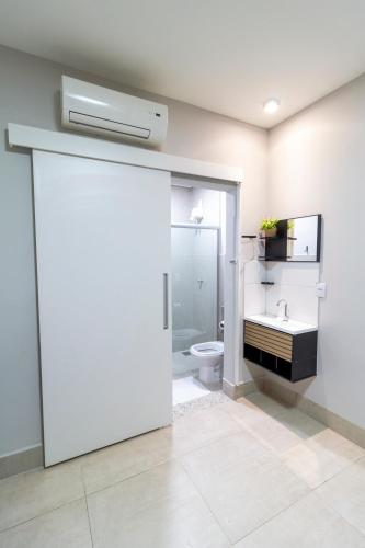 a white bathroom with a toilet and a sink at MOOVE Stay - Suite Cacau no centro in Uberlândia