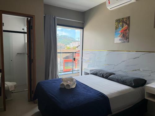 a bedroom with a bed with a blue blanket and a window at Pousada do Francês in Ubatuba