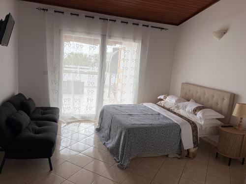 a bedroom with a bed and a chair and a window at tud dret in Santa Maria