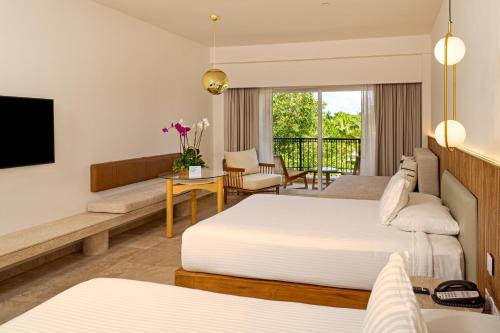 a hotel room with two beds and a television at Kimpton Tres Rios - All Inclusive in Playa del Carmen