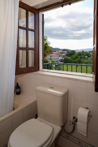 a white toilet in a bathroom with a window at Casa da Pedrada in Ponte da Barca