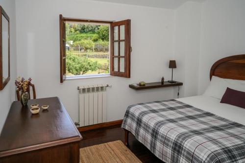 a bedroom with a bed and a window and a table at Casa da Pedrada in Ponte da Barca
