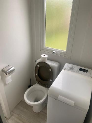 a small bathroom with a toilet and a window at Mobile home in Litteau