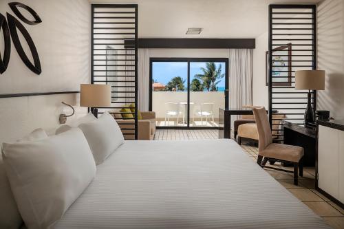 a bedroom with a large bed with a desk and chairs at Ocean Coral & Turquesa All Inclusive in Puerto Morelos