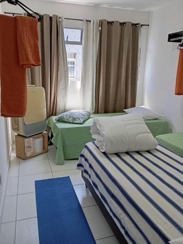 a room with two beds and a window at Espaço Jeito de Casa Hospedagem em Quarto Compartilhado in Recife