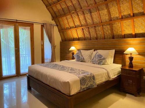 a bedroom with a large bed with a wooden ceiling at Griya Garden Penida in Nusa Penida