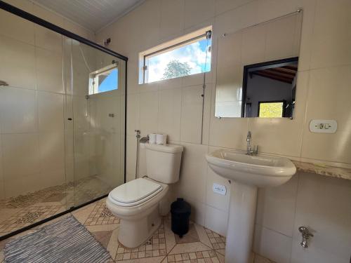a bathroom with a toilet and a sink and a shower at Villa da Vila Montanhas in Monte Verde