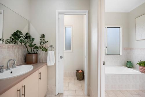 a white bathroom with a tub and a sink at Salt & Stay - Laid-Back Comfort by the Beach in Encounter Bay